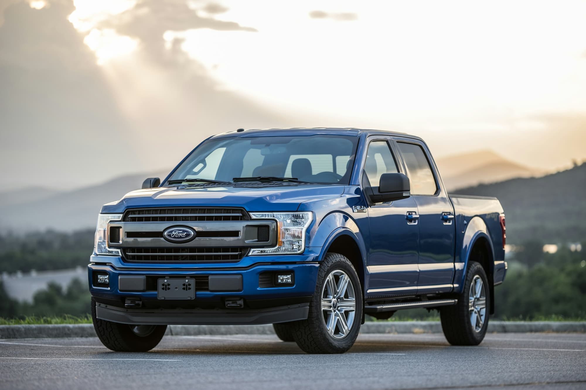 Blue Ford pickup truck parked at a mountain overlook at sunset